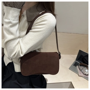 Detail of minimalist dark brown frosted leather shoulder bag shown in a lifestyle setting