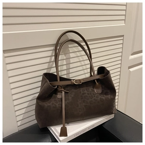 Macro shot of dark leopard print suede tote with elegant buckle strap and texture