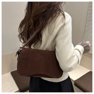 Brown matte suede underarm bag shown on a model with a minimalist shoulder strap style
