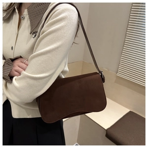 Detailed view of dark brown suede shoulder bag with minimalist design and curved bottom