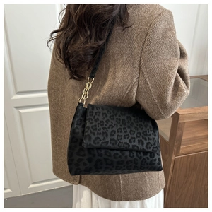 Rear view of a leopard print shoulder bag with gold chain strap on a model in a blazer