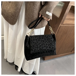 Detail of leopard print shoulder bag with gold chain strap worn with a tweed blazer