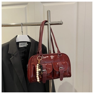 Detailansicht der burgunderroten Lackleder-Handtasche mit Taschen und Perlen-Anhänger