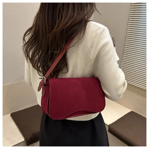 Detail of red suede underarm bag showing adjustable strap and silver metal hardware