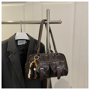 Detailansicht der dunkelbraunen Lackleder-Schultertasche mit Schnallentaschen und Anhänger