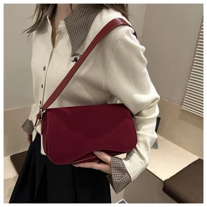 Detail view of burgundy matte leather shoulder bag with adjustable strap on a model