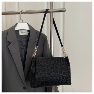 Detail of leopard print shoulder bag with gold chain strap on a blazer background