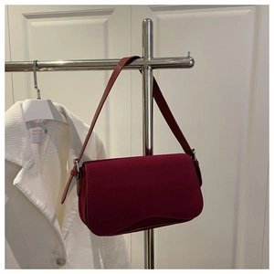 Detail of burgundy matte faux suede underarm bag with adjustable shoulder strap and silver buckle