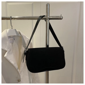 Detail of matte black underarm bag on silver rack with a white striped suit backdrop