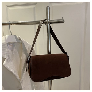 Detail view of dark brown suede shoulder bag with elegant flap and silver metal buckle