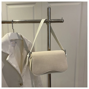 Close-up of minimalist ivory underarm bag with smooth leather flap on display