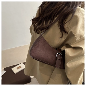Détail du sac bandoulière en daim marron foncé avec finitions cuir et boucle en métal rétro