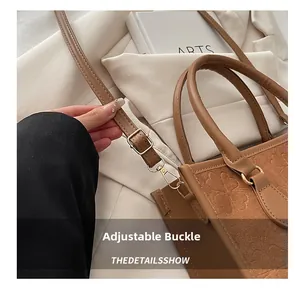 Detail of adjustable golden buckle and clover embossed pattern on brown PU leather bag