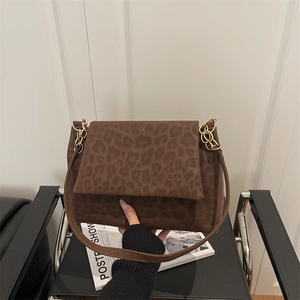 Leopard print crossbody bag with gold chain strap on a vintage leather chair