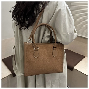 Detail of vintage brown tote bag featuring embossed clover textures and smooth leather handles