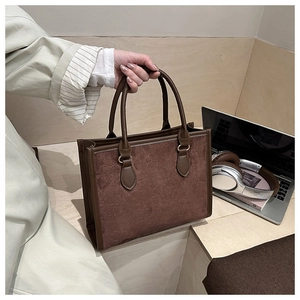 Detail of dark brown tote bag with embossed clover pattern and premium suede texture