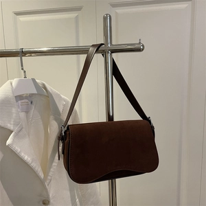 Brown suede underarm bag with wavy base design hanging on a silver hanger
