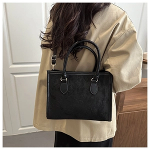Model view showing black four-leaf clover embossed shoulder bag with adjustable strap