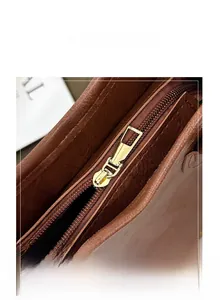 Macro detail of high-quality brown leather bucket bag featuring a polished gold metal zipper