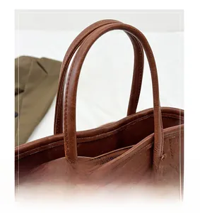 Close-up of brown litchi grain leather texture and durable handles on a retro bucket bag