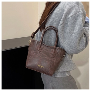 Detail of dark brown bucket bag showing retro wrinkled texture and gold lettering