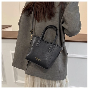 Detail of black bucket bag showing leather texture and golden Fashion & BaG logo