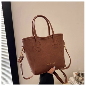 Detailed close-up of brown PU bucket bag with gold text and slender shoulder strap