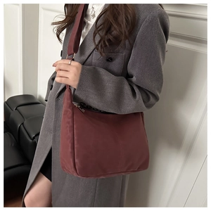 Close-up of a burgundy crescent tote bag with wide strap and high-quality nylon texture