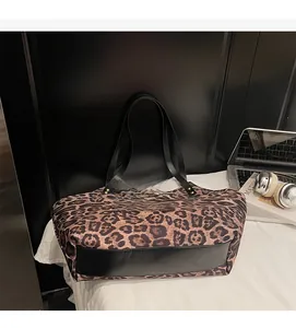 Detail of leopard print tote bag with black leather stitching and metal rivets