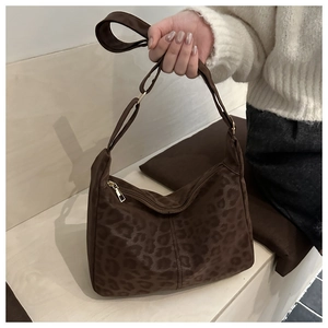 Detail of dark brown leopard print hobo bag with knotted strap and gold zipper closure