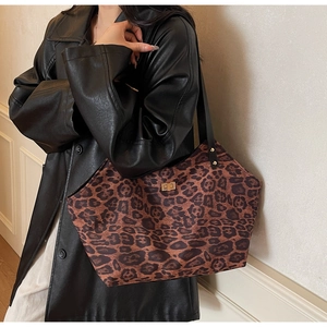 Detail of leopard print tote bag featuring a golden twist-lock and black leather straps