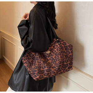 Detail of leopard print tote bag featuring a gold twist-lock closure and black leather straps