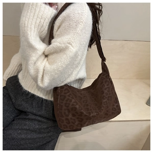 Detail of a leopard print underarm bag paired with a white sweater in a lifestyle setting