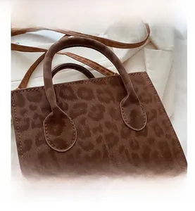 Close-up of brown leopard print handbag with plush texture and cylindrical handle