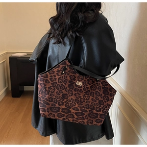 Detail of leopard print tote bag featuring a metal turn-lock closure and slim black straps