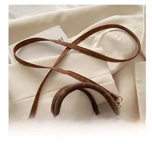 Detail of adjustable slender shoulder strap on brown suede bag with gold hardware