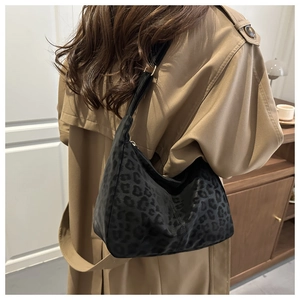 Detail of a large leopard print tote bag in black, styled with a classic beige trench coat
