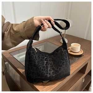 Detail of dark leopard print hobo bag showing fabric texture and adjustable strap