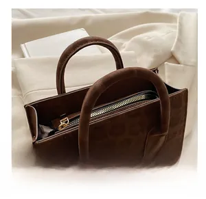 Detail of a dark brown suede bucket bag with gold hardware and comfortable round handles