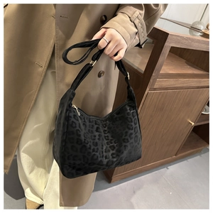 Detail of black leopard print crescent shoulder bag with adjustable strap worn by model