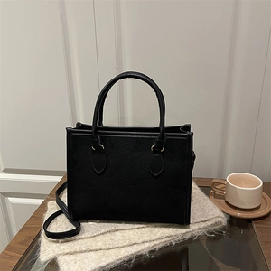 Chic black tote bag with clover embossing, featuring gold hardware and a shoulder strap