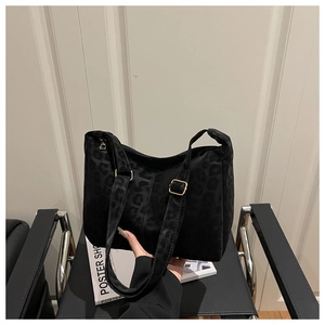 Detailed view of black leopard print tote bag with gold metal buckle and matte texture