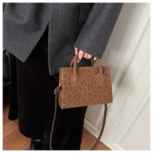 Detail of trendy leopard print tote bag with soft texture and refined metal hardware