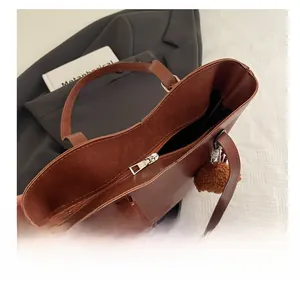 Vista dall'alto della borsa tote in pelle marrone con cerniera e ciondolo a pompon soffice