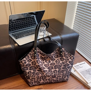 Detail of leopard print tote bag with black leather straps and gold metal logo plaque