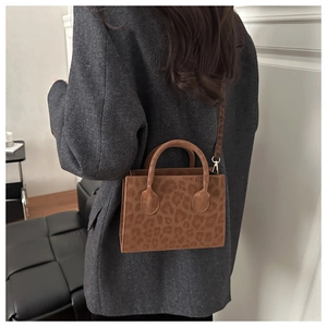 Detailed view of brown leopard print crossbody bag featuring gold hardware and dual handles