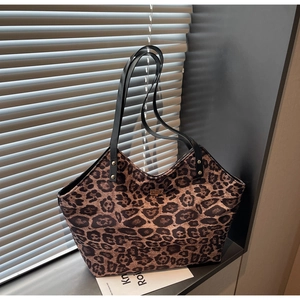 Detail of leopard print tote bag featuring black slim straps and golden metal clasp lock