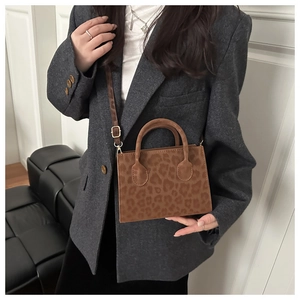 Model wearing a brown leopard print crossbody bucket bag with adjustable shoulder strap