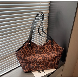 Detail of leopard print tote bag with golden turn-lock and black straps on a windowsill