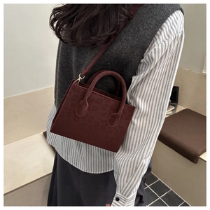 Detail of dark burgundy bucket bag with leopard embossing and gold metal fasteners